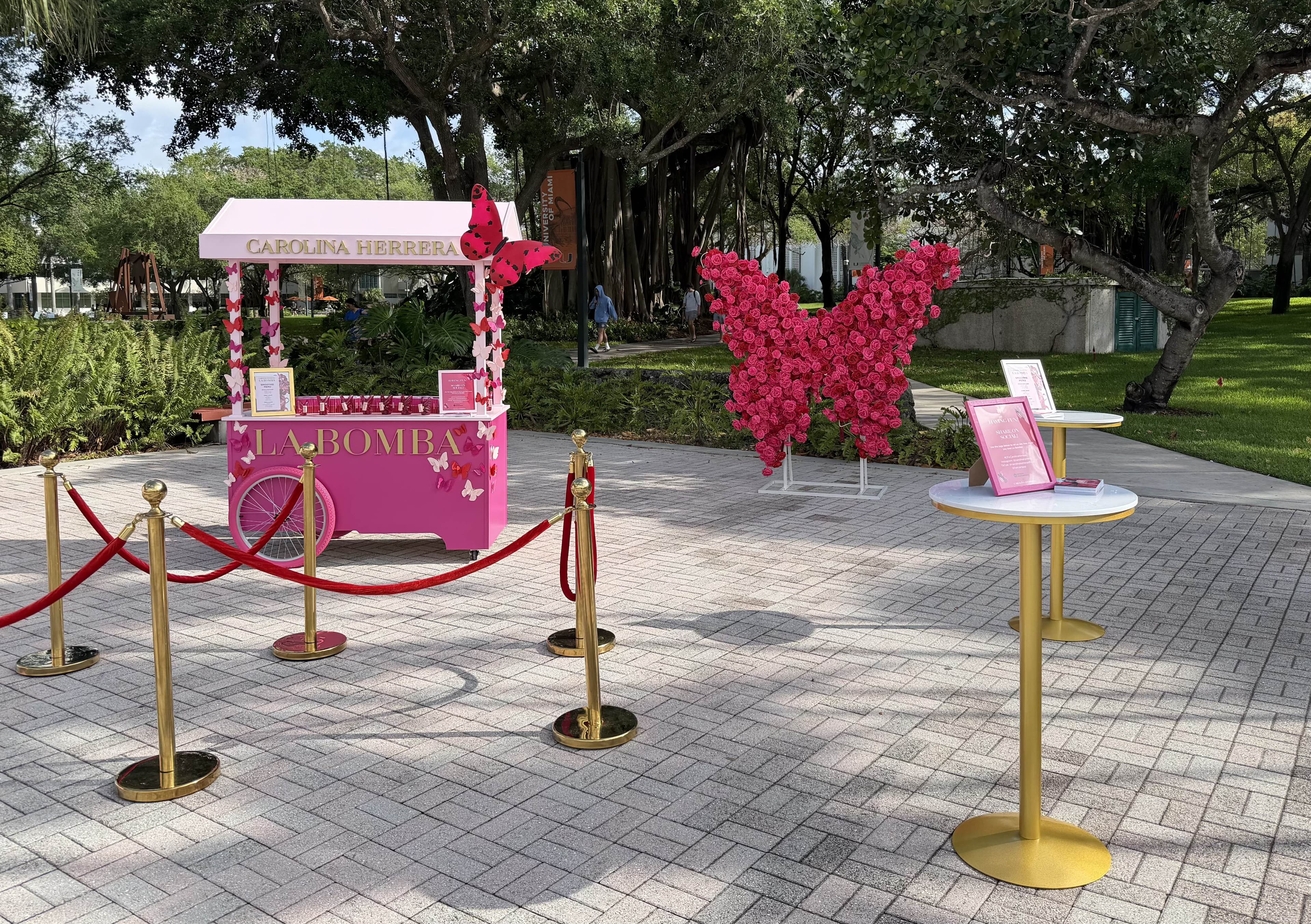 Carolina Herrera La Bomba outdoor event setup with pink cart and butterfly decorations