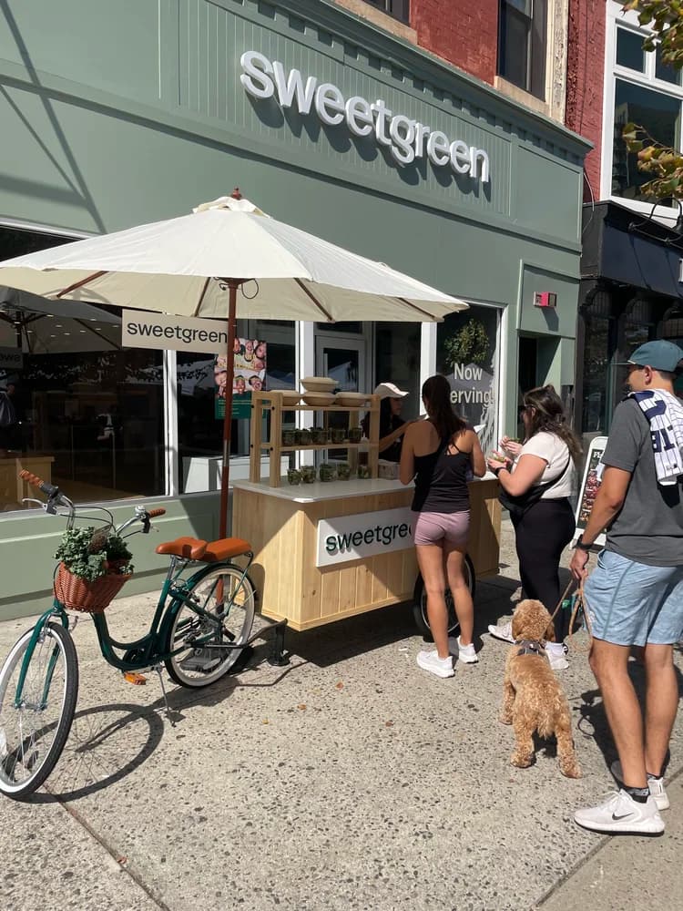 Custom wooden Sweetgreen sampling cart on a sidewalk